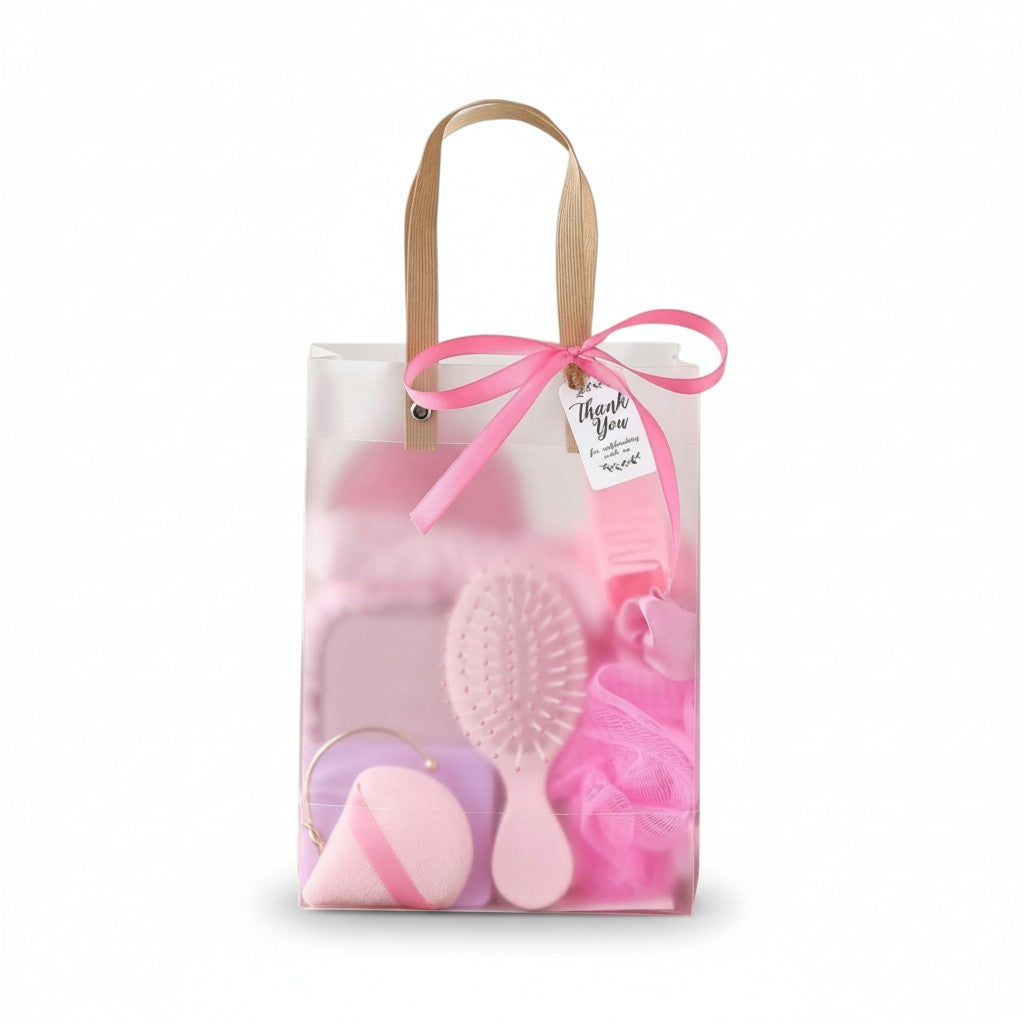 Giftplug pink beauty essentials gift set featuring a hairbrush, bath sponge, and makeup tools in a transparent bag.