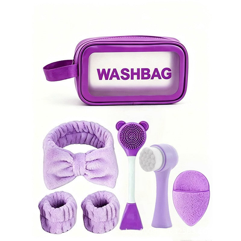 Giftplug 6-piece purple skincare set with bow headband, wrist cuffs, silicone brushes, and a transparent washbag.
